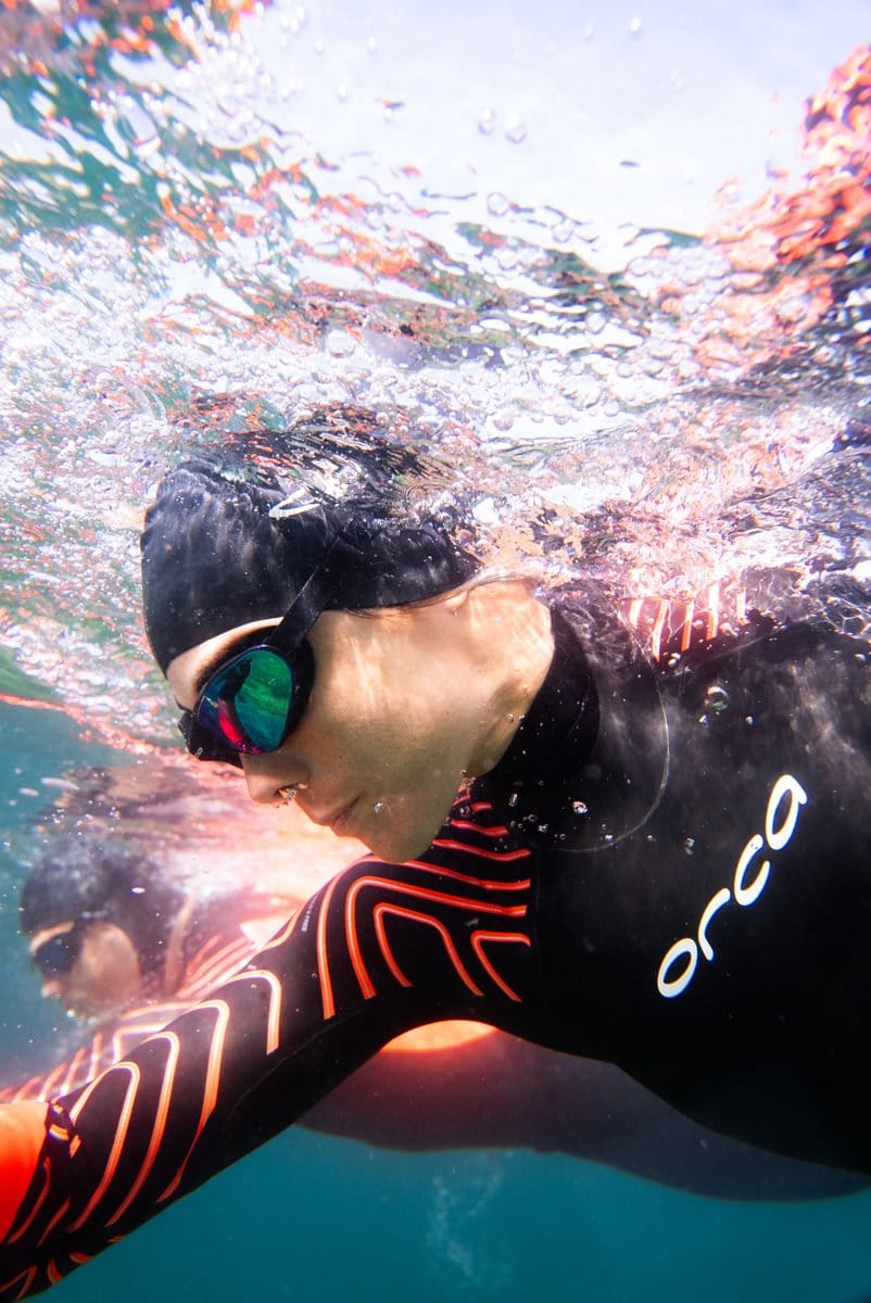 Woman swimming in wetsuit, cap & goggles